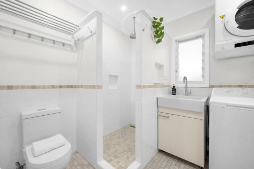 a white bathroom with a toilet and a sink at AXL Orion Beach Home: Beach front in Vincentia