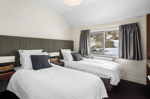 a hotel room with two beds and a window at Kooloora Lodge in Perisher Valley