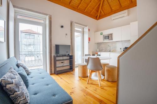a living room with a blue couch and a kitchen at Belas Artes Apartments in Porto