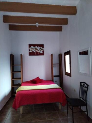 - une chambre avec un lit rouge et une chaise dans l'établissement Carmen Graciela, à Álamos