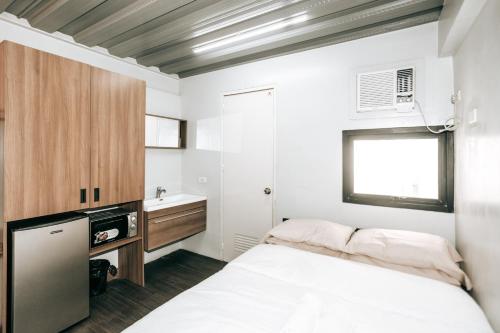 a small bedroom with a bed and a sink at District Inn in Manila