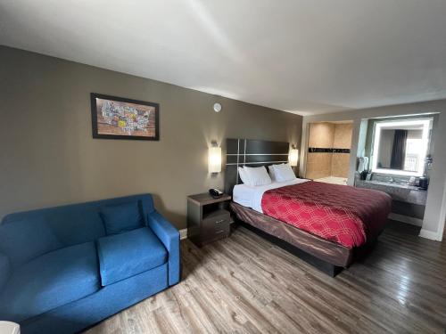 a hotel room with a bed and a blue couch at Econo Lodge Inn & Suites Murfreesboro Shopping District in Murfreesboro