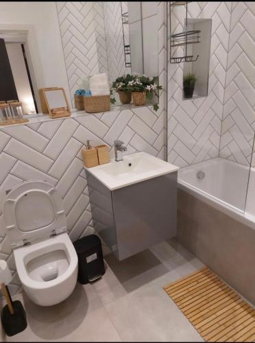 a bathroom with a toilet and a sink and a tub at Modern 2bed Sutton in Sutton