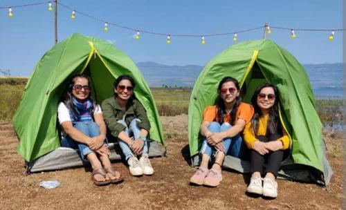 a group of people sitting in front of tents at Malshej Ghat Hill Stastion Camping in Otūr