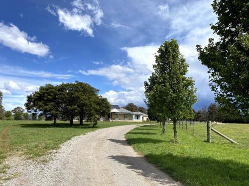 un camino de tierra frente a una casa con árboles en The Farm 2460 - Southern Highlands, en Canyonleigh