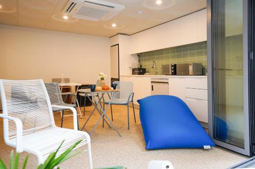 a kitchen with white chairs and a blue ottoman at SimpleStay Hotel in Jongno in Seoul
