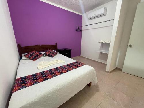 - une chambre dotée d'un lit avec un mur violet dans l'établissement Departamento en Pomoca, à Palenque