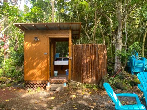 a wooden outhouse with a gate and blue chairs at Manta Soul Jungle Geodome in Kealakekua