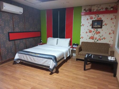 a bedroom with a bed and a couch in it at Sky Hotel in Hwaseong