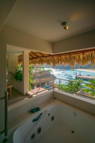 a bath tub in a room with a view of the ocean at Hotel Casa Justina in Puerto Ángel