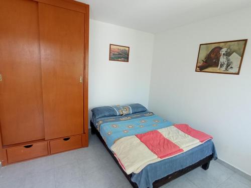 a small bedroom with a bed and a cabinet at Casa Flamboyant in Querétaro
