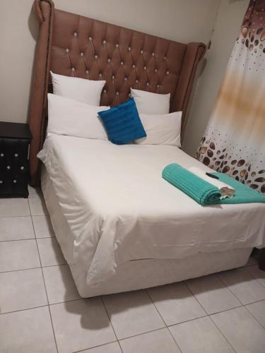 a bed with white sheets and blue pillows on it at 26 Zea avenue Arcon Park Guest House in Vereeniging