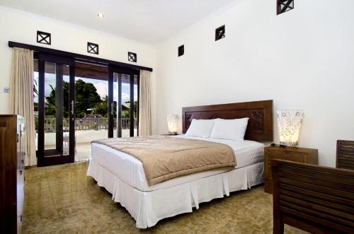 a bedroom with a large bed and a balcony at Teja Home Stay in Ubud