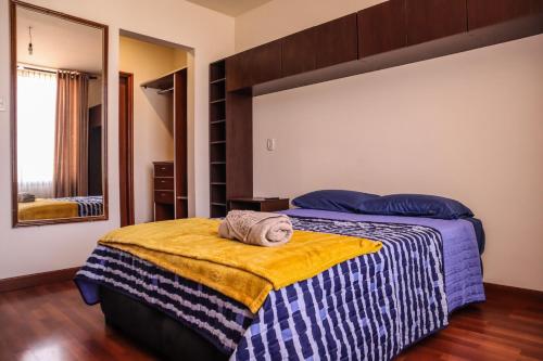 ein Schlafzimmer mit einem Bett mit gelber Decke und einem Spiegel in der Unterkunft Amplio Departamento en la mejor zona de Cochabamba in Cochabamba