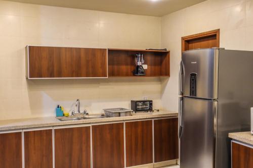 eine Küche mit einem Kühlschrank aus Edelstahl und Holzschränken in der Unterkunft Amplio Departamento en la mejor zona de Cochabamba in Cochabamba