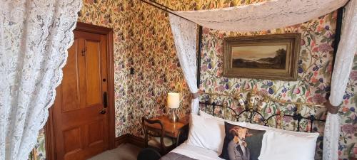 a bedroom with a canopy bed with floral wallpaper at Pheasant Lodge in Paparoa