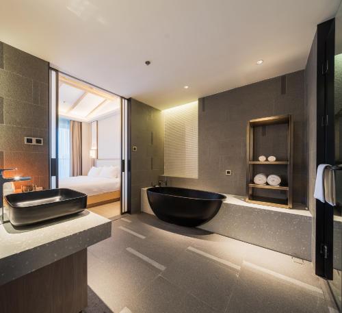 a bathroom with a black tub and a bedroom at Hentique Manna Tangshan in Nanjing