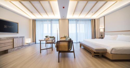 a bedroom with a bed and a desk and a tv at Hentique Manna Tangshan in Nanjing