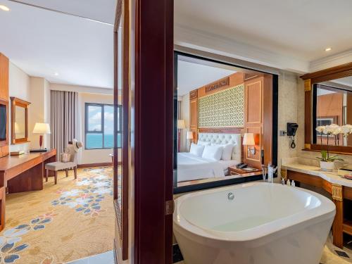a bathroom with a tub and a bedroom with a bed at DLG Hotel Danang in Da Nang