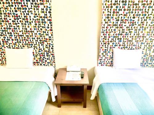 twee bedden in een kamer met een tafel ertussen bij Hotel Happy Holiday Ishigaki in Ishigaki Island