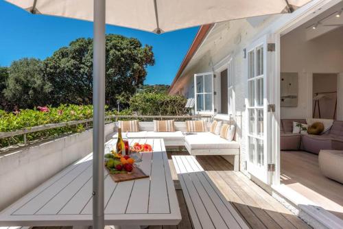 un patio al aire libre con mesa y sombrilla en The Hibiscus - Coast & Country, en Onetangi