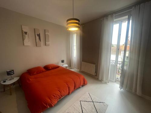 ein Schlafzimmer mit einem Bett mit einer orangefarbenen Decke in der Unterkunft L échappée Belle in Rochefort