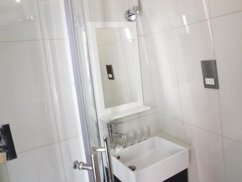 a white bathroom with a sink and a mirror at Earls Court Garden Hotel in London