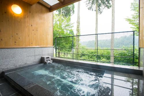 a swimming pool in a building with a large window at Yamashitako Lodge in Yufu