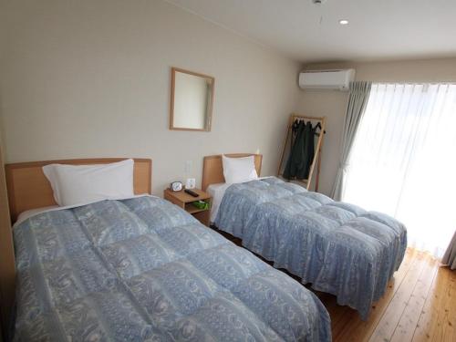 1 dormitorio con 2 camas y ventana en Yamashitako Lodge, en Yufu