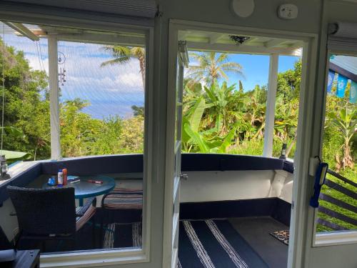 a screened in porch with a table and a view of the ocean at Cozy jungle boat hideaway with stunning ocean view in Kealakekua