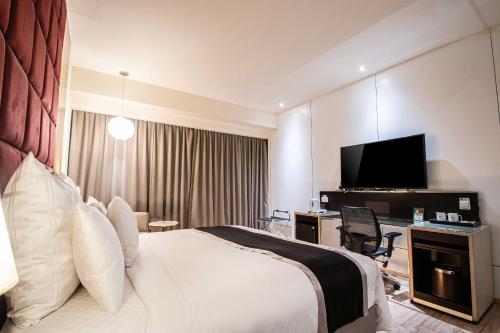 a hotel room with a bed and a flat screen tv at 168 Motel-Hsinchu in Hsinchu City