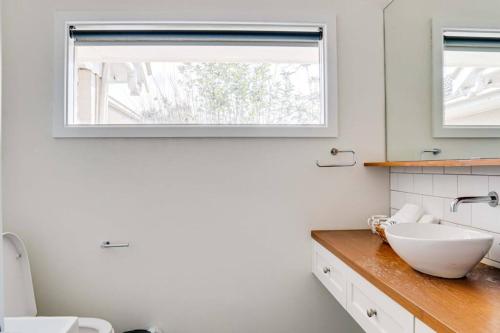 La salle de bains est pourvue d'un lavabo blanc et d'une fenêtre. dans l'établissement Heritage Holiday House No.17, à Wonga Park