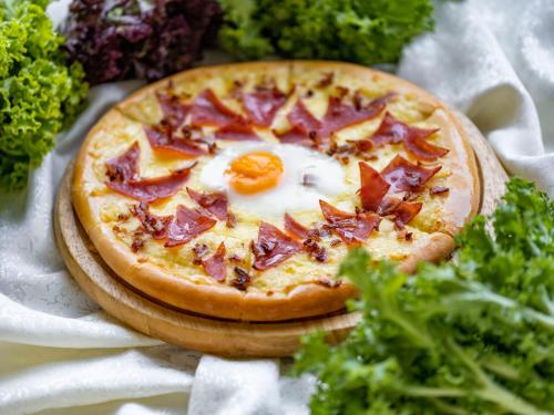 a pizza sitting on top of a table with broccoli at DLG Hotel Danang in Da Nang