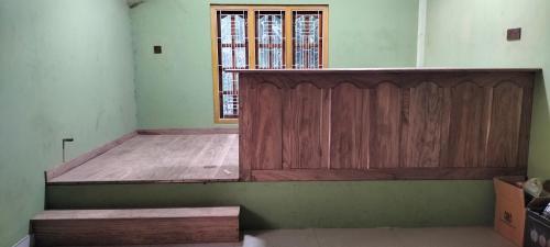 Habitación con cama de madera y ventana en MR JEY Deluxe, en Jaffna