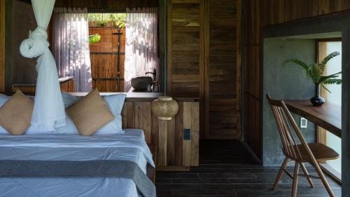 a bedroom with a bed and a desk and a table at The Ruong Resort in Vung Tau