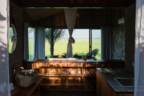 a kitchen with a window with a view of a field at The Ruong Resort in Vung Tau