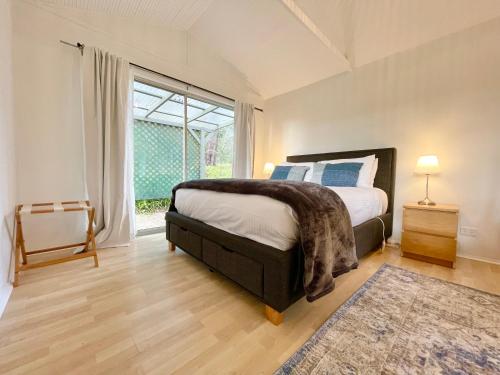a bedroom with a bed and a large window at Norman Lindsay Cottage in Faulconbridge