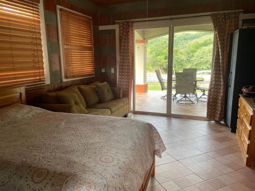 een slaapkamer met een bed, een bank en een patio bij Boca De Los Rios River Site in Penonomé