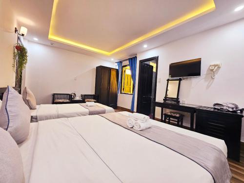 Habitación de hotel con 2 camas y TV de pantalla plana. en Win Homestay Hoi An, en Hoi An