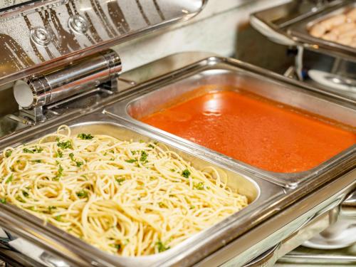 a tray of spaghetti in a pan with sauce at DLG Hotel Danang in Da Nang