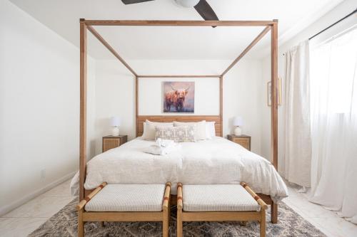 a bedroom with a canopy bed with two chairs at Lighthouse Guest Suites in Fort Lauderdale