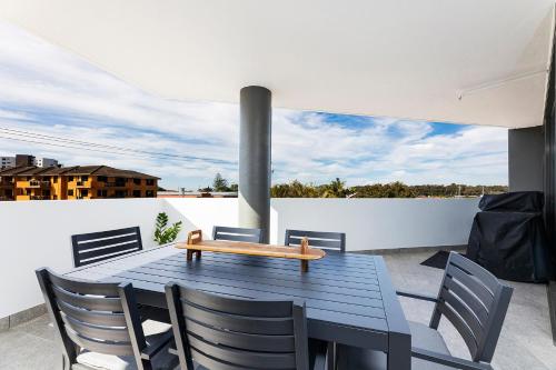 a table with chairs and a bench on a balcony at Serenity at Solaris 101 in Forster