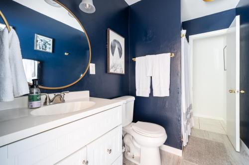 Baño azul con aseo y espejo en Lighthouse Guest Suites, en Fort Lauderdale