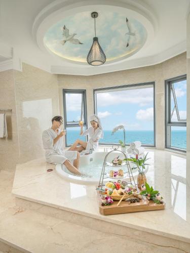 a man and woman sitting in a bath tub in a bathroom at DLG Hotel Danang in Da Nang
