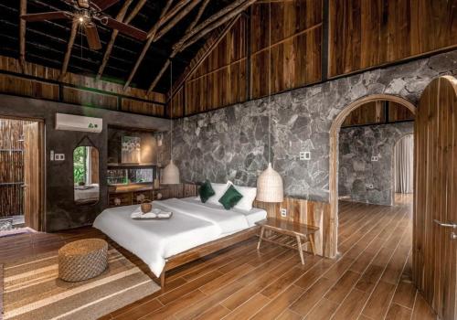a bedroom with a bed and a table in a room at The Ruong Resort in Vung Tau