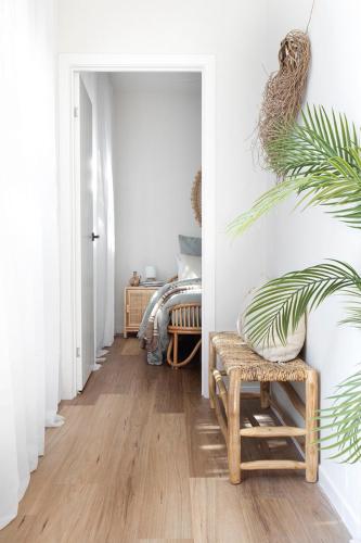 a hallway with white walls and wooden floors and a chair at Currumbin Beach 1 bedroom Studio - steps from the beach! in Gold Coast