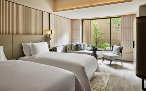 京都市にあるデュシタニ京都のベッド2台とリビングルームが備わるホテルルームです。