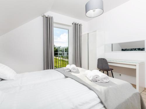 a white bedroom with a bed and a chair at Comfortable holiday complex in Jastrzebia Gora in Jastrzębia Góra