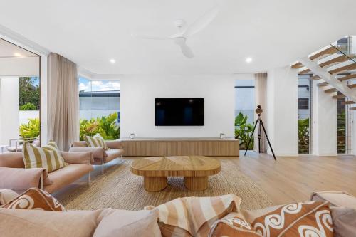 ein Wohnzimmer mit einem Sofa und einem TV in der Unterkunft Beachside, luxury resort living in Yaroomba