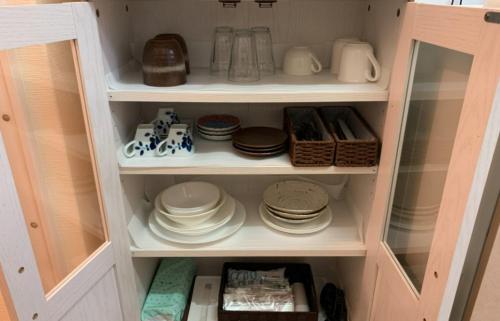 a cupboard filled with plates and dishes in a kitchen at Oyado Kinokuniya Daikokumachi in Nagasaki